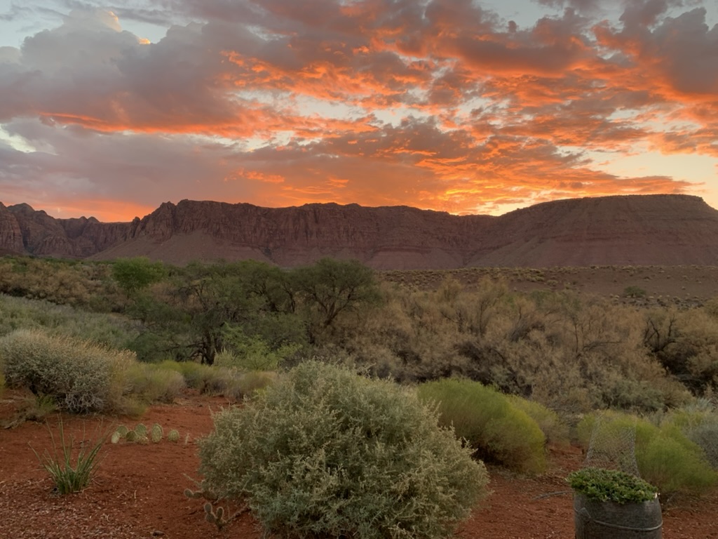 Sun set and pink/orange clouds over a red rock mountain