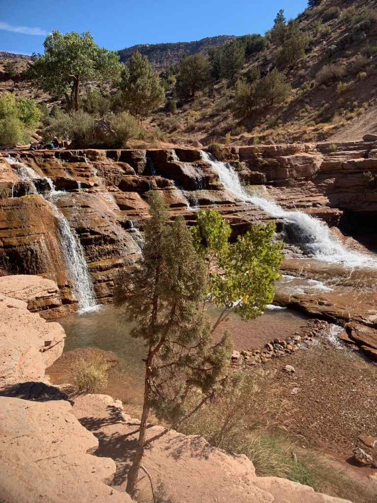 Waterfall going down multi-leveled red rock in the desert