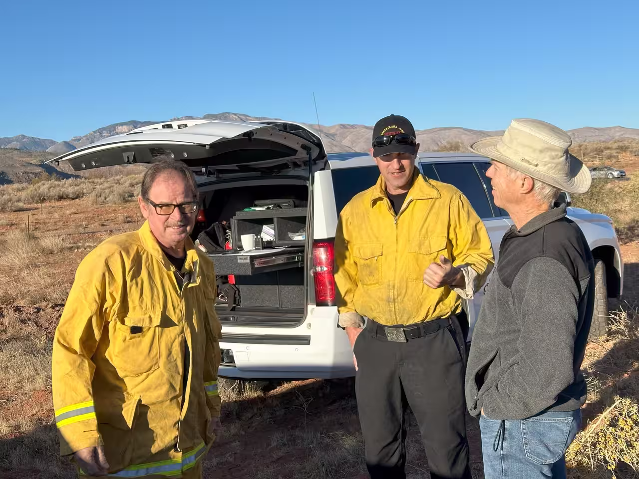 Con Fulde, Fire Department Division Chief, stands with two other men in yellow fire safety coat and gear