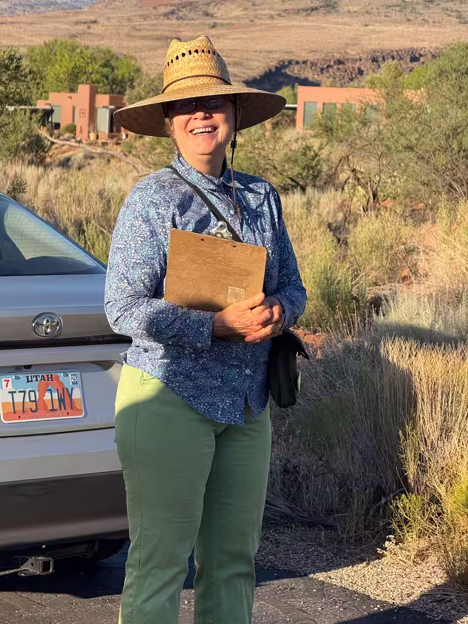 Shauna Goldberry, Conservation botanist and STEAM educator stands in a desert landscape holding a clipboard